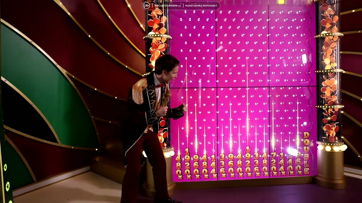 Il conduttore di Crazy Time davanti alla parete rosa del Pachinko